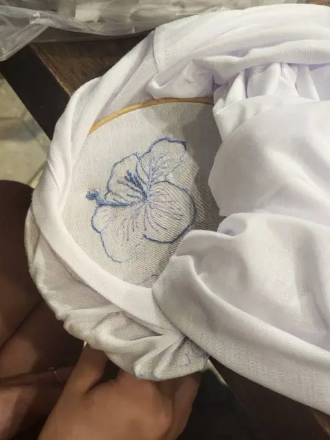 A blue hibiscus flower embroidered on a white T-shirt
