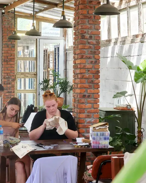Guests embroider at a long table in the brick-walled garden café
