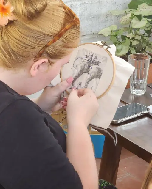 A guest embroiders a detailed black and white design in a hoop