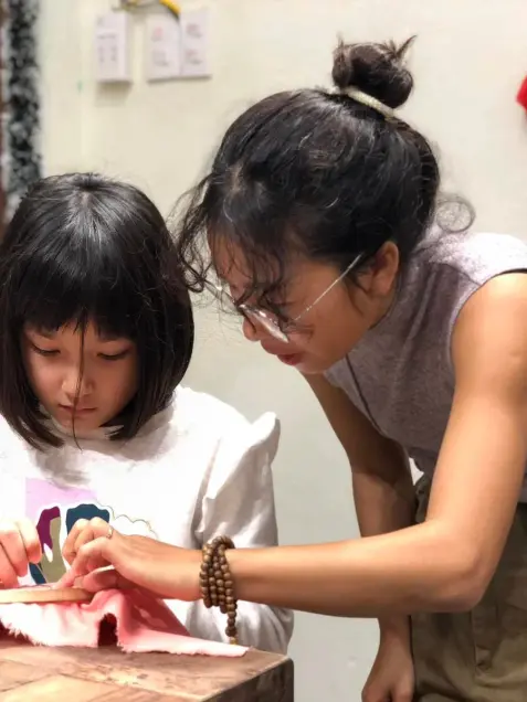 A child gets one-to-one help with a fabric craft project