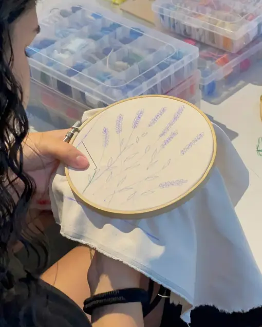 An embroidery hoop with lavender stems stitched in purple thread