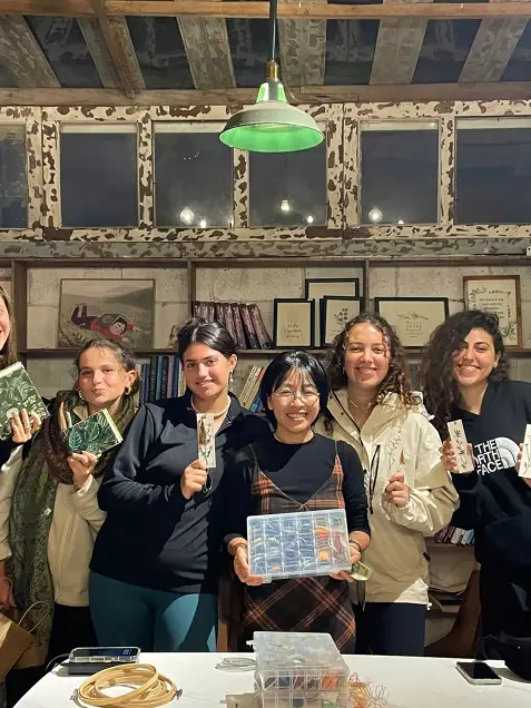 A group shows embroidered bookmarks and notebooks after an evening workshop