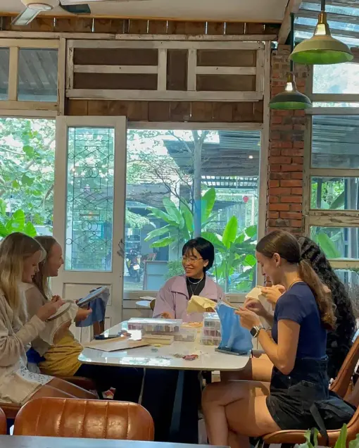 Guests embroider at a table beside open doors to the garden